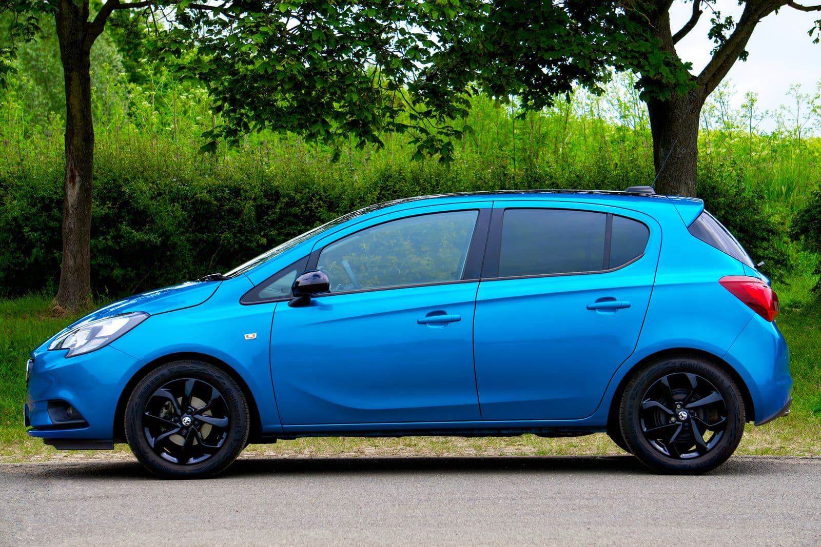 Blue compact car on a tree-lined road